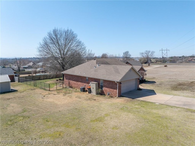 view of home's exterior with fence, driveway, an attached garage, a yard, and brick siding