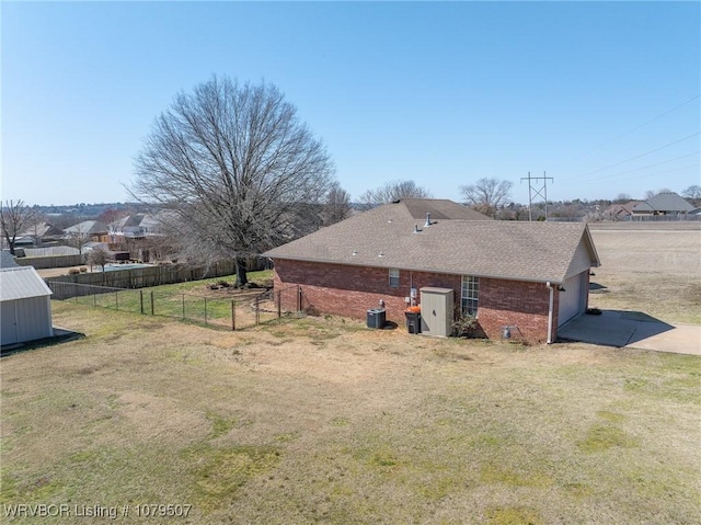 view of side of home with fence, driveway, an attached garage, a lawn, and brick siding