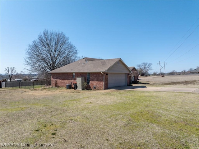 exterior space featuring brick siding, fence, concrete driveway, a front yard, and a garage