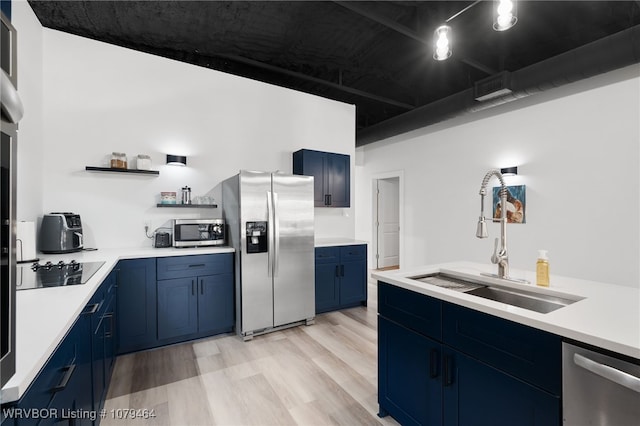 kitchen with open shelves, light wood-style flooring, appliances with stainless steel finishes, a sink, and blue cabinets