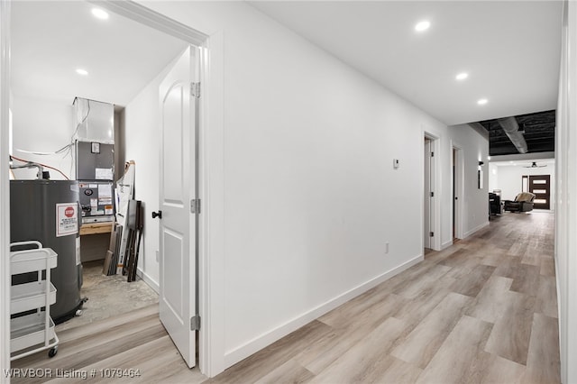 corridor with recessed lighting, light wood-style flooring, baseboards, and electric water heater