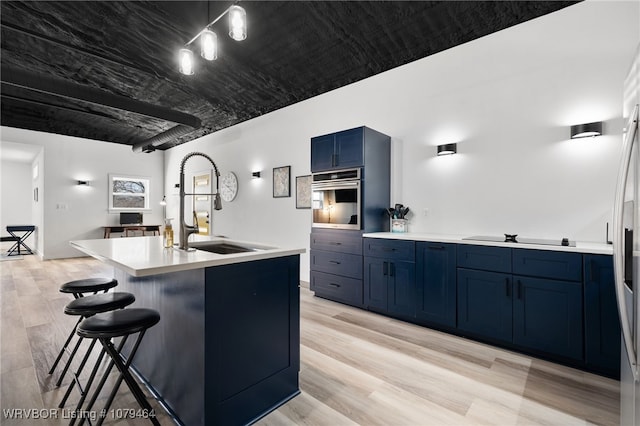 kitchen featuring light wood finished floors, light countertops, blue cabinets, oven, and black electric cooktop