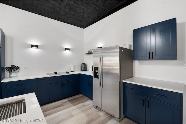 kitchen featuring light wood-style flooring, light countertops, black electric cooktop, blue cabinetry, and stainless steel refrigerator with ice dispenser