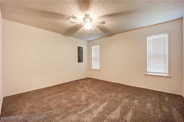 empty room with electric panel, ceiling fan, a textured ceiling, and dark colored carpet