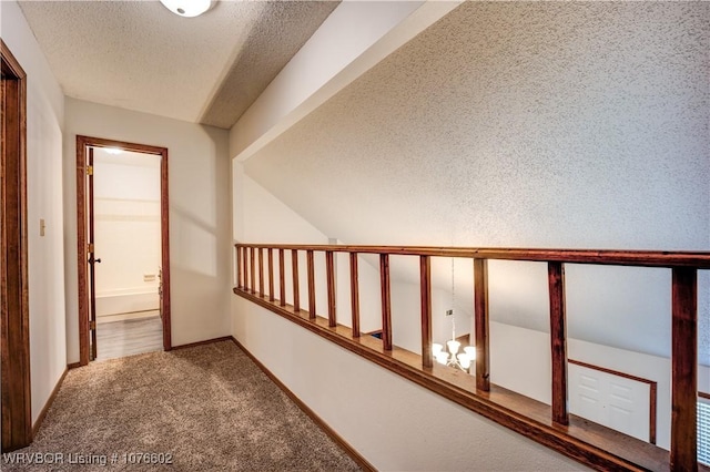 hallway featuring carpet, a textured ceiling, and vaulted ceiling