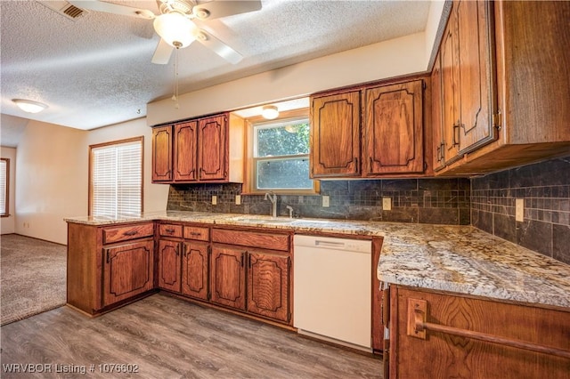 kitchen featuring ceiling fan, dishwasher, sink, a textured ceiling, and light wood-type flooring