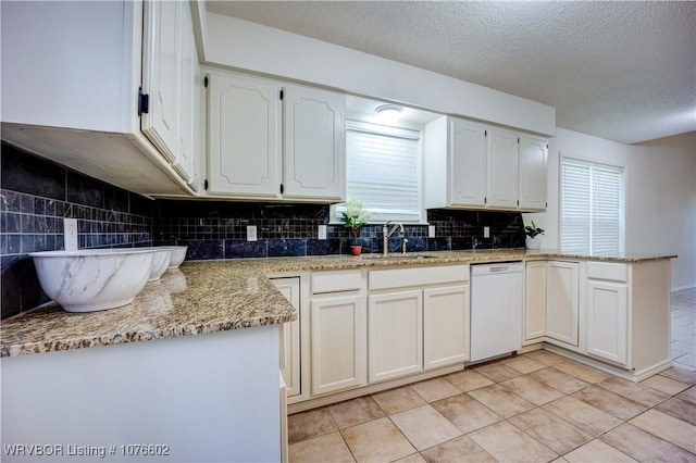 kitchen with white dishwasher, white cabinets, light tile patterned floors, and a textured ceiling