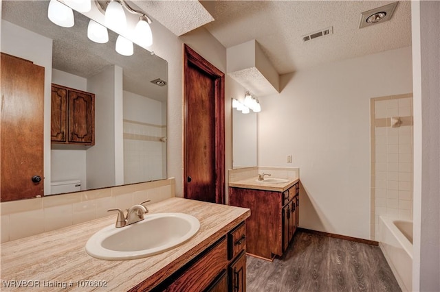 full bathroom featuring hardwood / wood-style floors, a textured ceiling, toilet, shower / tub combination, and vanity