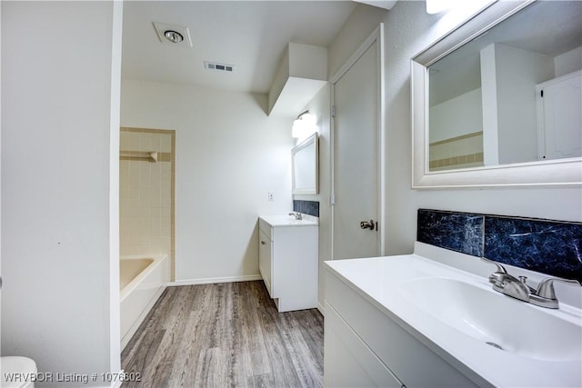 bathroom with hardwood / wood-style floors, vanity, and tiled shower / bath