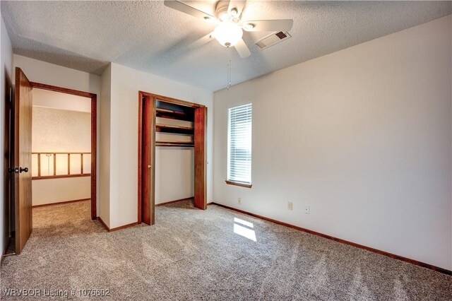 unfurnished bedroom with a textured ceiling, ceiling fan, light carpet, and a closet