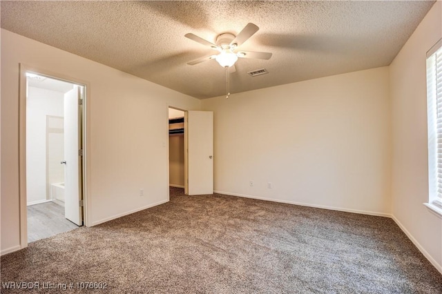 unfurnished bedroom featuring carpet, a textured ceiling, ceiling fan, connected bathroom, and a closet