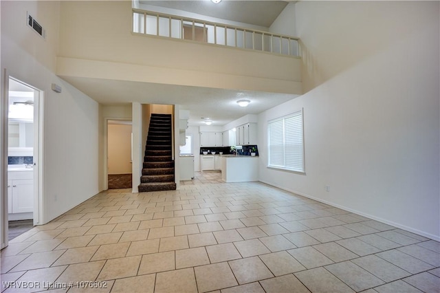 unfurnished living room with light tile patterned floors and a high ceiling