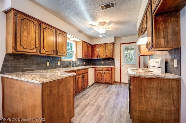 kitchen with a textured ceiling, white appliances, light hardwood / wood-style flooring, and a healthy amount of sunlight