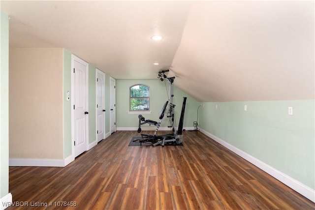 exercise room with dark hardwood / wood-style flooring and vaulted ceiling