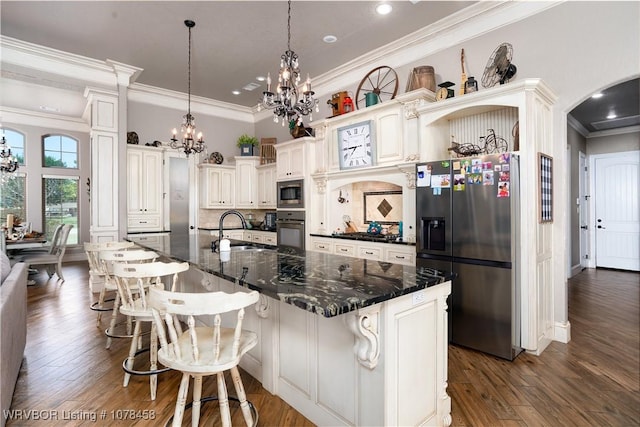 kitchen with a kitchen bar, appliances with stainless steel finishes, sink, and a large island with sink