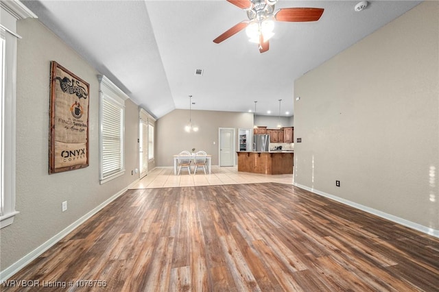 1075 Maple Ridge Dr, Greenwood, AR 72936 - unfurnished living room with light wood finished floors, ceiling fan with notable chandelier, baseboards, vaulted ceiling, and visible vents