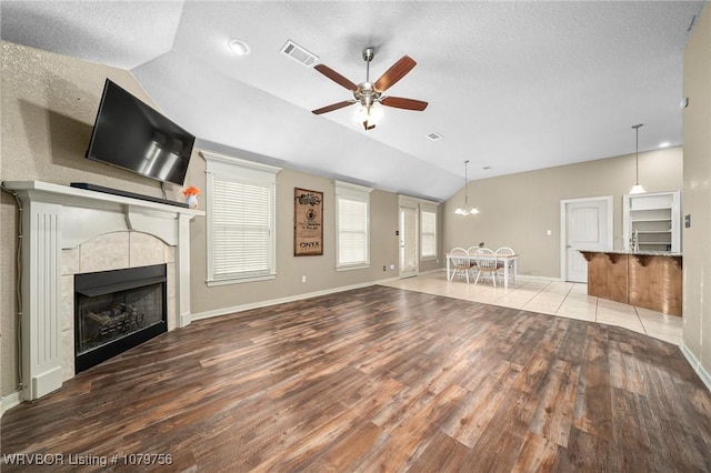 1075 Maple Ridge Dr, Greenwood, AR 72936 - unfurnished living room featuring a textured ceiling, baseboards, ceiling fan with notable chandelier, lofted ceiling, and light wood-style flooring