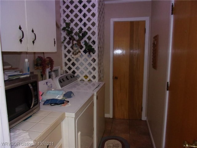 clothes washing area with cabinets, washer and clothes dryer, and light tile patterned flooring