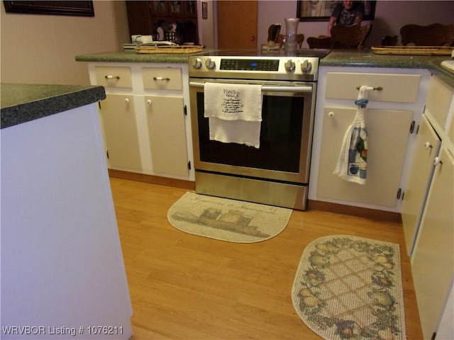 kitchen featuring white cabinets, stainless steel range with electric stovetop, and light wood-type flooring