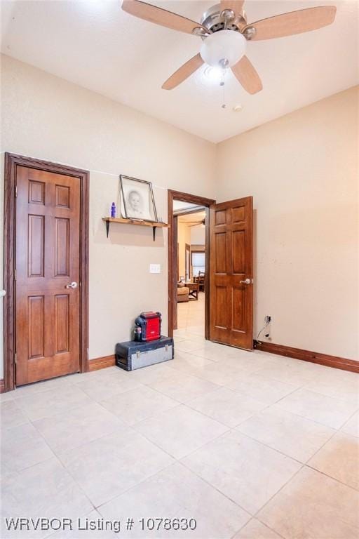 empty room with ceiling fan and light tile patterned floors