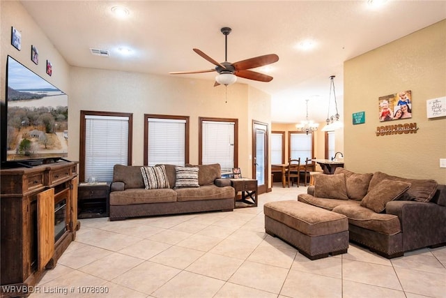 living room with lofted ceiling, ceiling fan with notable chandelier, and light tile patterned flooring