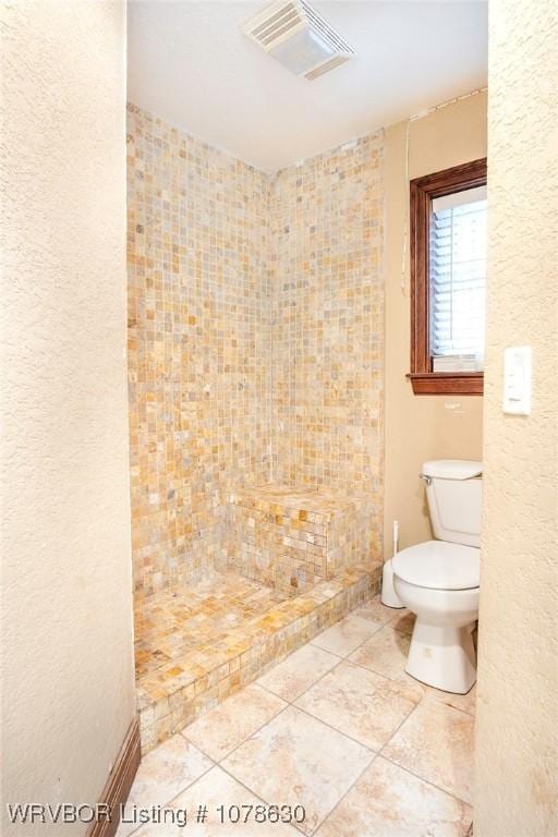 bathroom with toilet, tile patterned flooring, and a shower