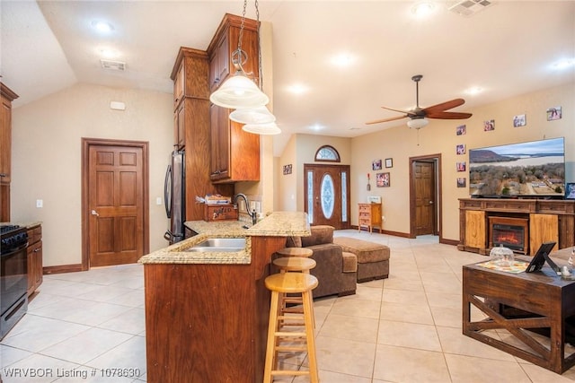 kitchen featuring sink, a breakfast bar area, stainless steel fridge, hanging light fixtures, and kitchen peninsula