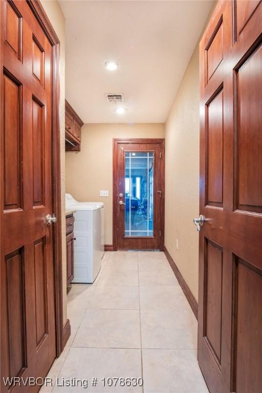 corridor with light tile patterned flooring and separate washer and dryer