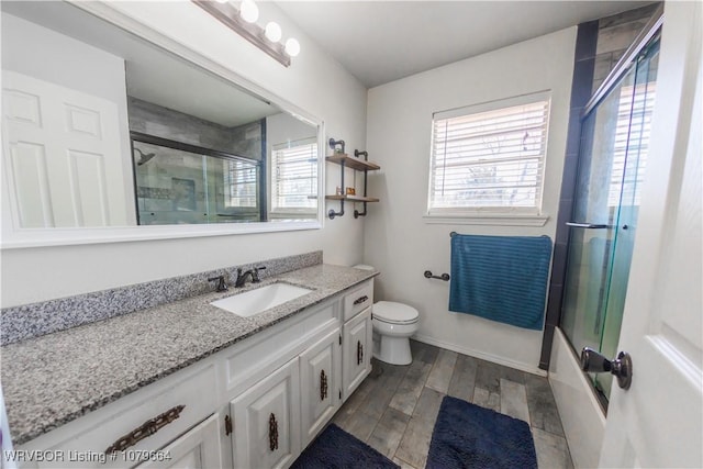 full bathroom featuring vanity, toilet, wood finished floors, and a wealth of natural light