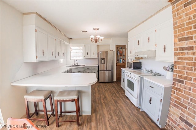 kitchen with under cabinet range hood, a peninsula, an inviting chandelier, stainless steel appliances, and a sink