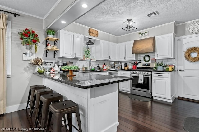 kitchen featuring sink, stainless steel range oven, kitchen peninsula, white cabinets, and custom range hood