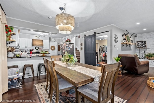 dining room featuring a textured ceiling, dark wood-type flooring, crown molding, a barn door, and a notable chandelier