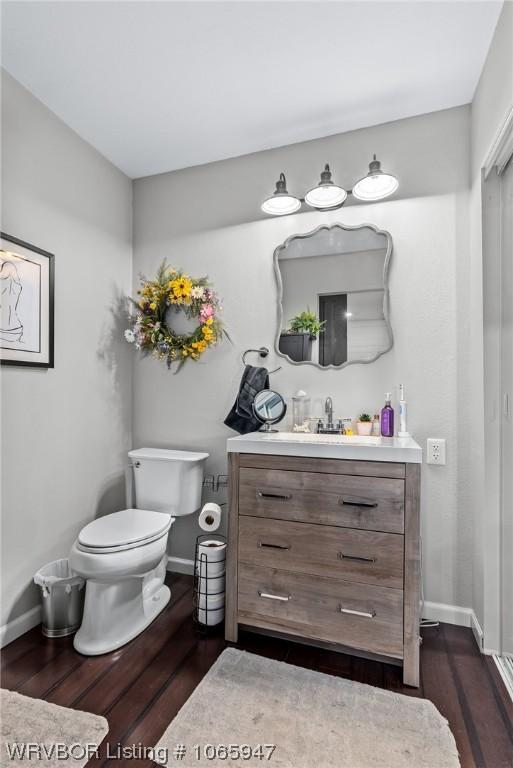 bathroom with wood-type flooring, vanity, and toilet