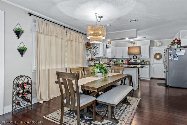 dining area featuring dark wood-type flooring, a textured ceiling, and a notable chandelier