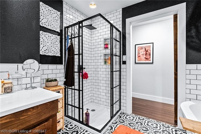 bathroom featuring vanity, a tile shower, and wood-type flooring