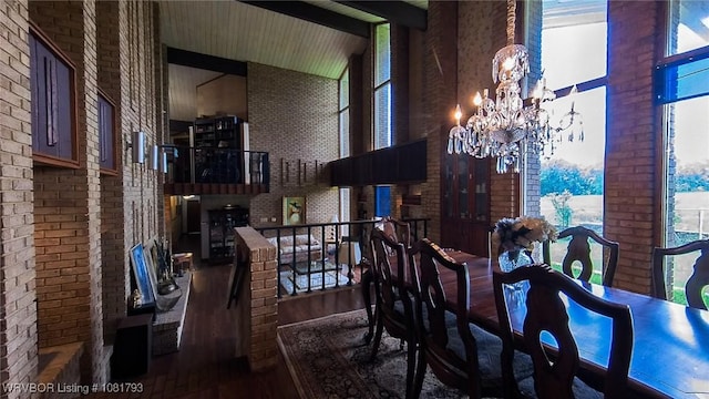 935 County Road 3456, Clarksville, AR 72830 - dining area featuring wood finished floors, brick wall, a chandelier, a towering ceiling, and healthy amount of natural light