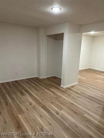 spare room featuring a textured ceiling, wood finished floors, and baseboards