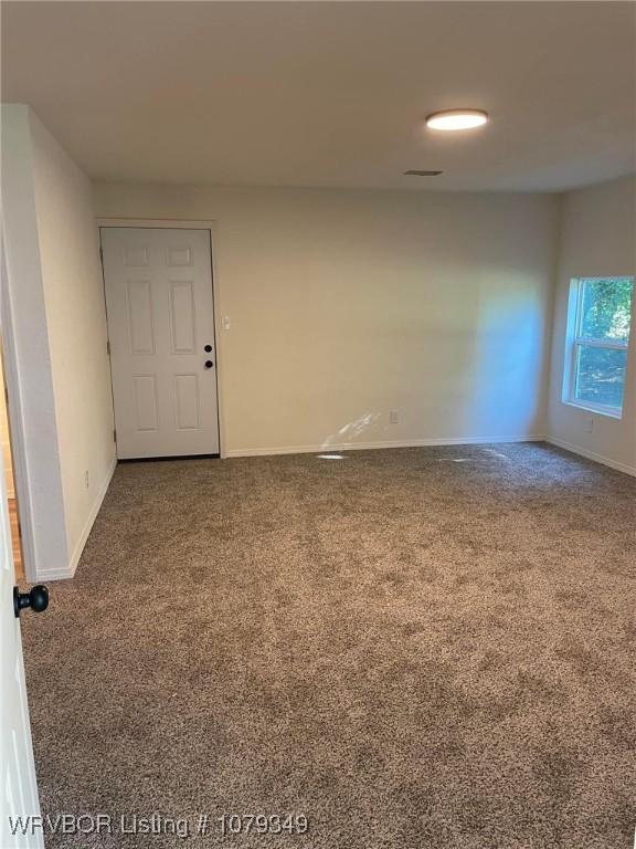 empty room featuring carpet, visible vents, and baseboards