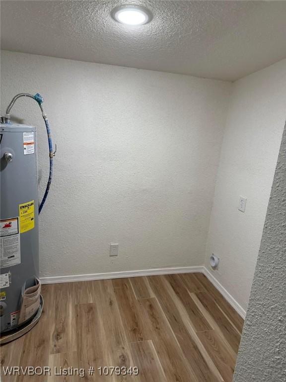 interior space with water heater, a textured ceiling, baseboards, and wood finished floors