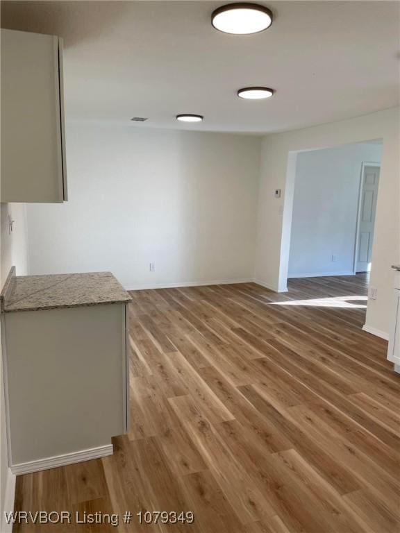 spare room with light wood-type flooring, visible vents, and baseboards