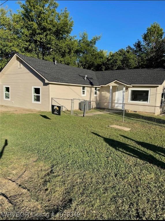 rear view of house featuring a yard and fence