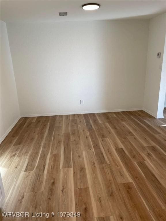 unfurnished room with baseboards, visible vents, and wood finished floors