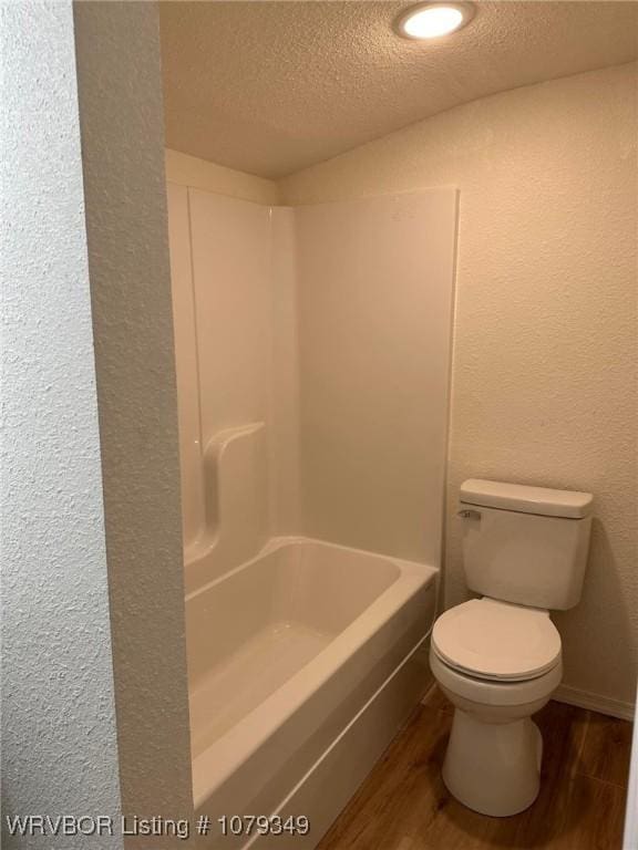 full bathroom with a textured ceiling, a textured wall, wood finished floors, and toilet