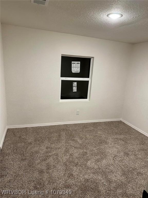 spare room with a textured ceiling, baseboards, and carpet flooring