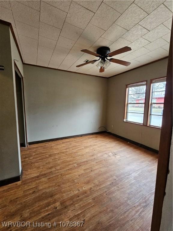 unfurnished room with crown molding, wood-type flooring, and ceiling fan