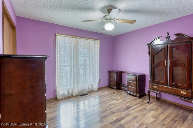 misc room with ceiling fan, a textured ceiling, and light hardwood / wood-style flooring