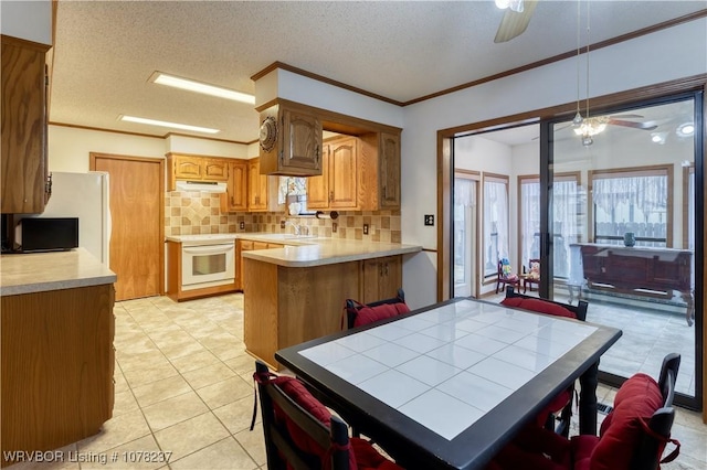 kitchen with kitchen peninsula, backsplash, a textured ceiling, white oven, and sink