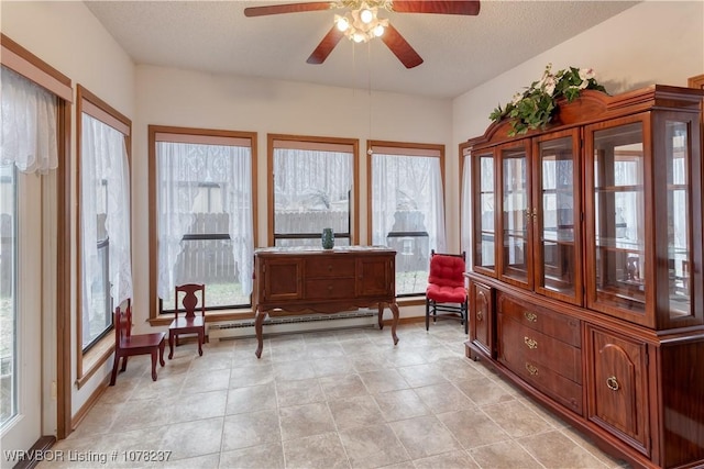 sunroom featuring ceiling fan, plenty of natural light, and a baseboard heating unit