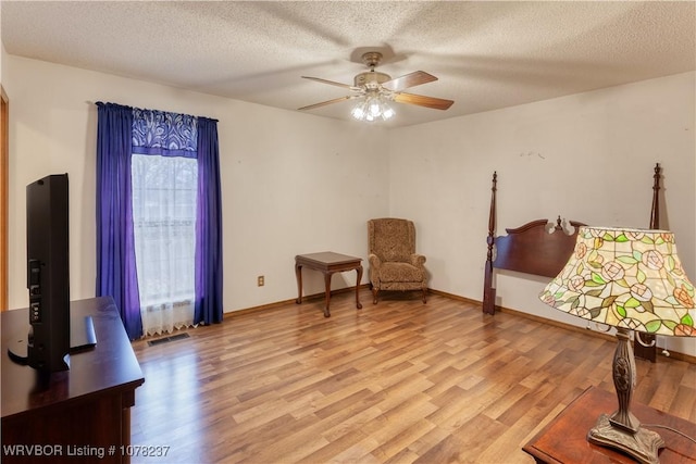 living area featuring ceiling fan, a textured ceiling, and light hardwood / wood-style flooring