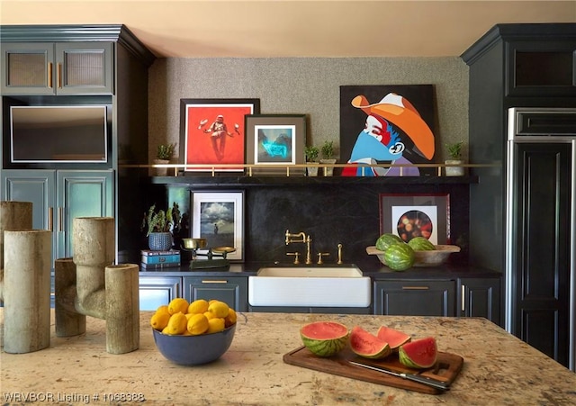 bar featuring paneled built in fridge, sink, and tasteful backsplash